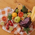 A vibrant flat lay of assorted fresh fruits on a checkered cloth over a wooden surface, perfect for healthy lifestyle concepts.